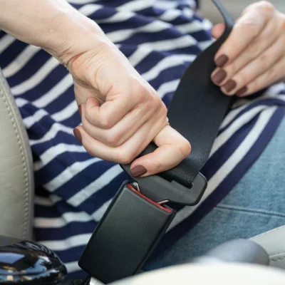 Eine Frau schließt den Sicherheitsgurt im Auto