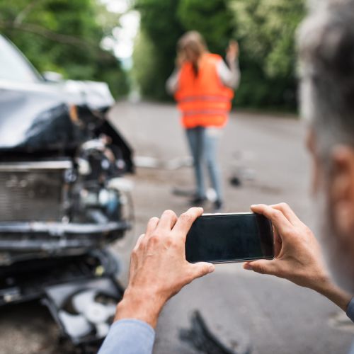Mann macht ein Bild von einem beschädigten Auto nach einem Unfall